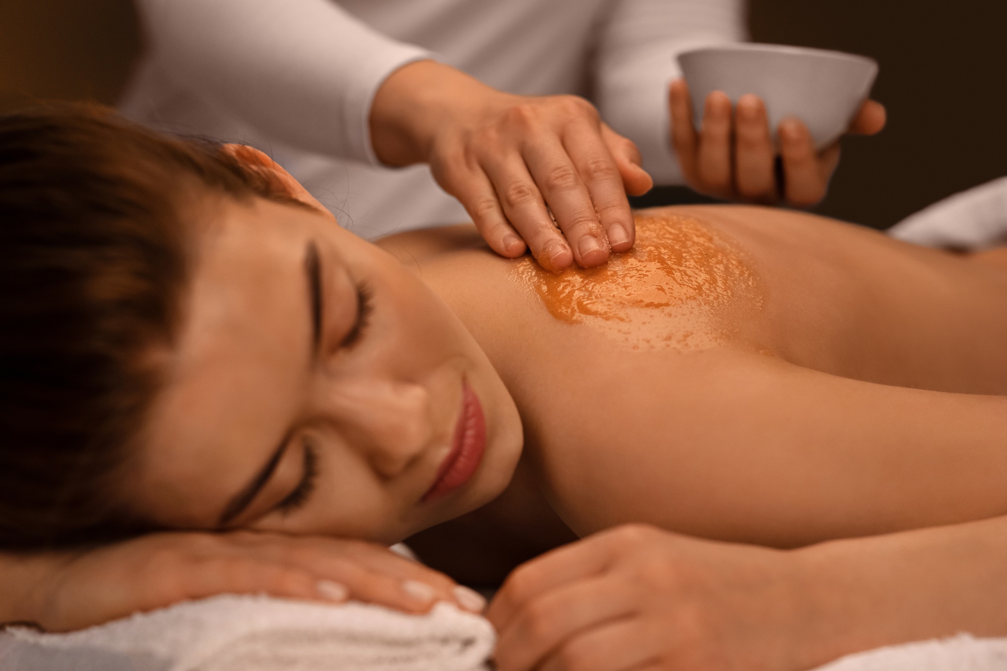 Closeup of sleeping lady getting body treatment at spa